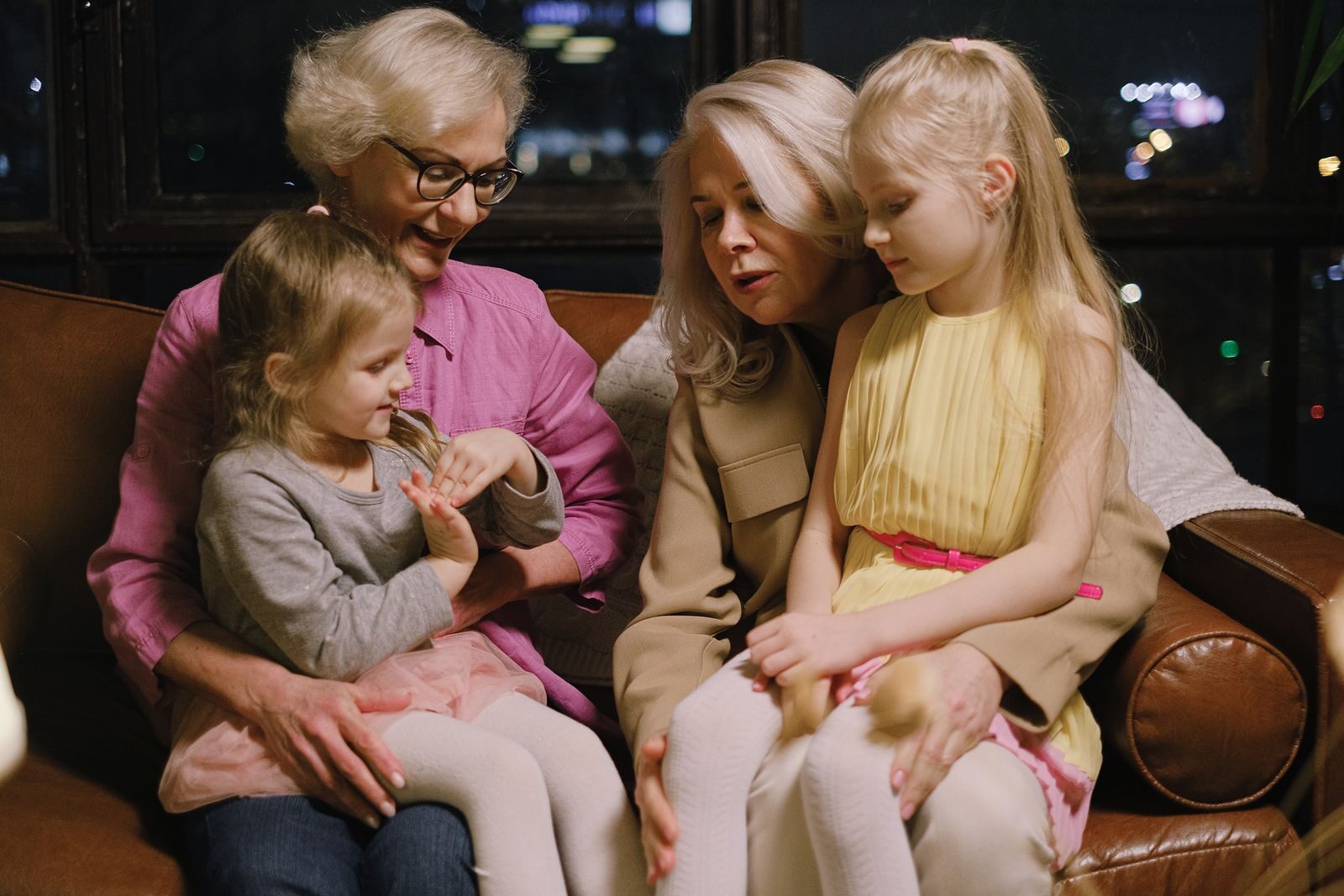 Photo by Anna Shvets A warm family moment indoors with two grandmothers and two granddaughters sitting together on a sofa.