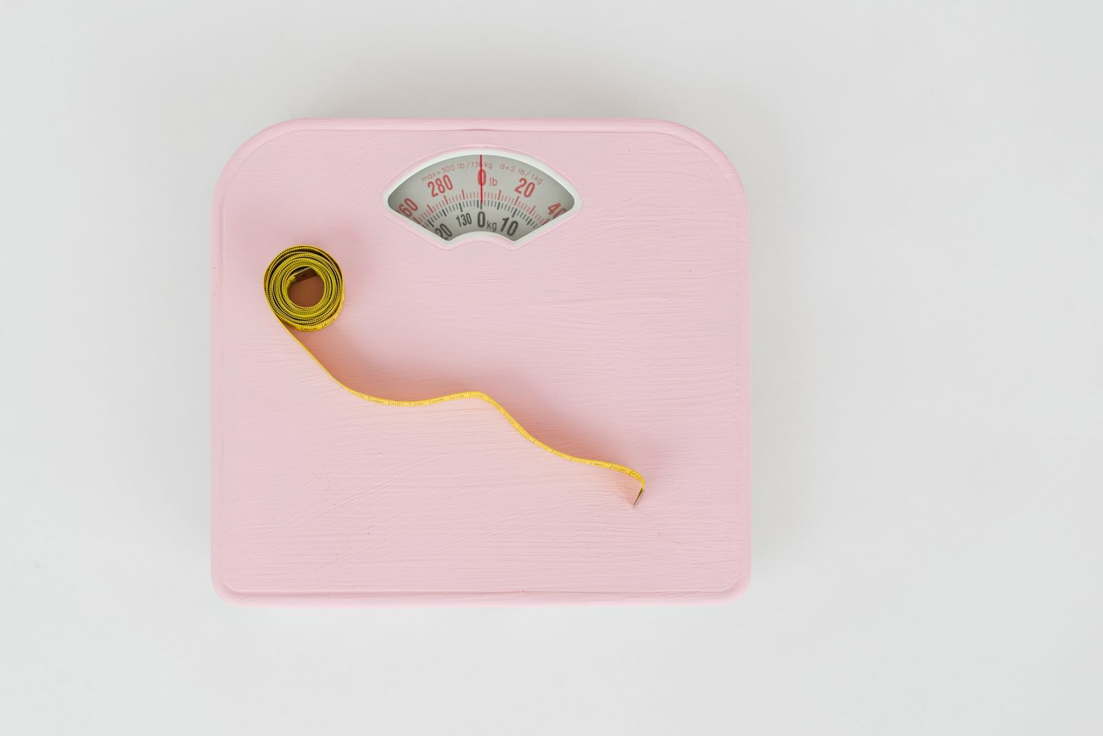 Top view of floor scales for weight control and measuring tape for controlling body shapes on white background