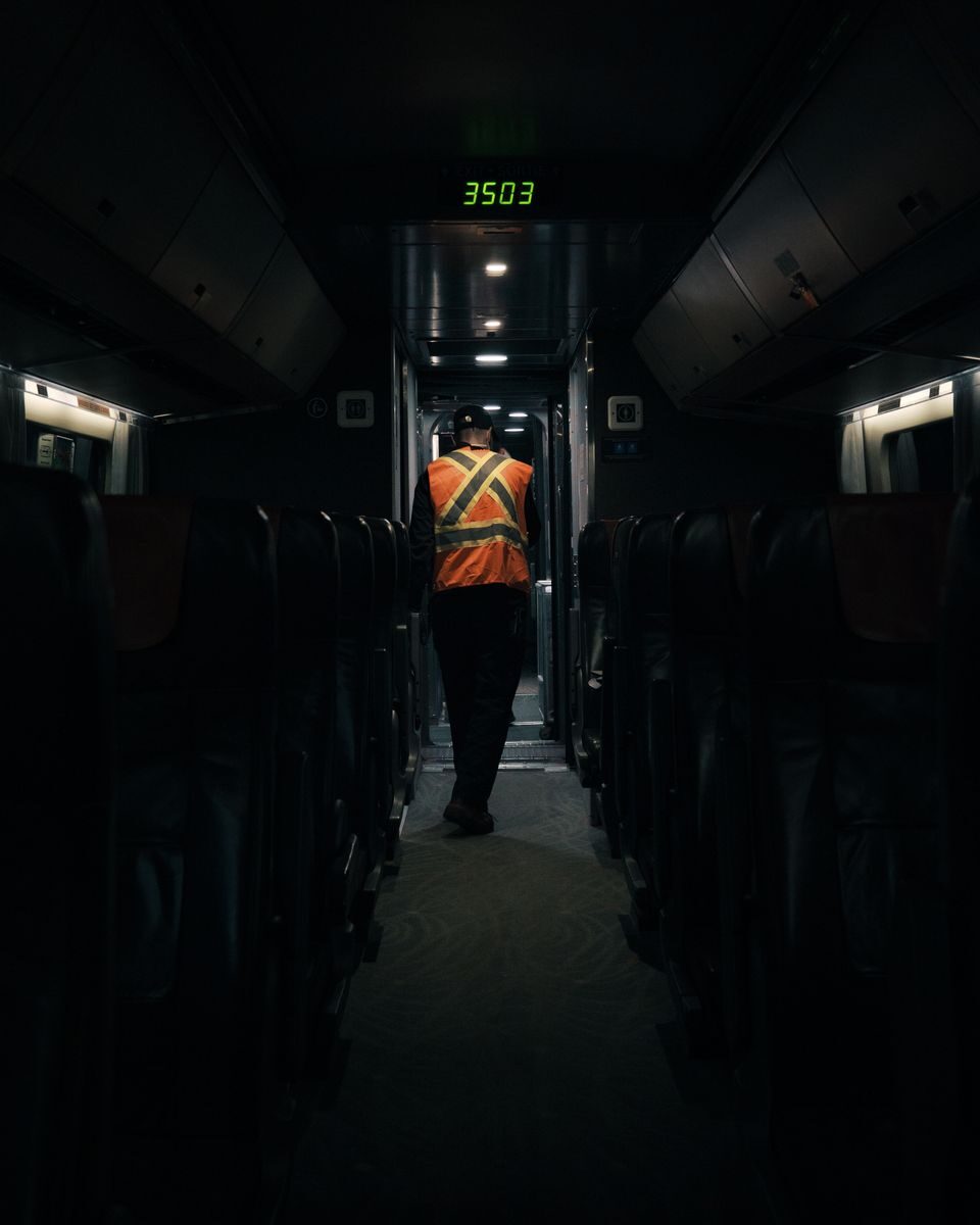 Train personnel walking down a dimly lit aisle in Montreal, Canada.
